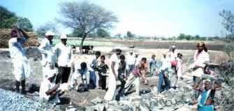 Villagers prepare small stones using a blasting machine from an old mine